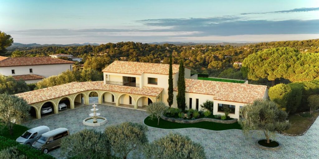 Luxueuse Villa Provençale avec Vue Panoramique Vue aérienne d'une grande villa provençale avec toits de tuiles, cour pavée, fontaine et vaste paysage forestier méditerranéen.